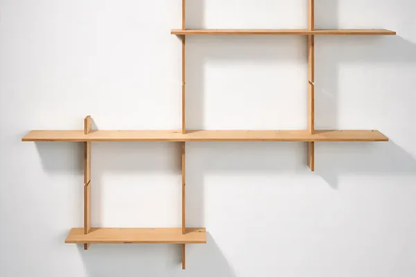 Photographie montrant une étagère murale en bois clair composée de casiers carrés et rectangulaires asymétriques.